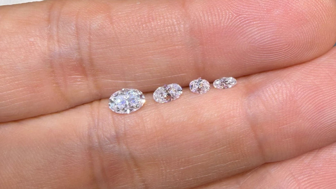 Four sizes of oval moissanite laid in a row on a hand, largest to smallest