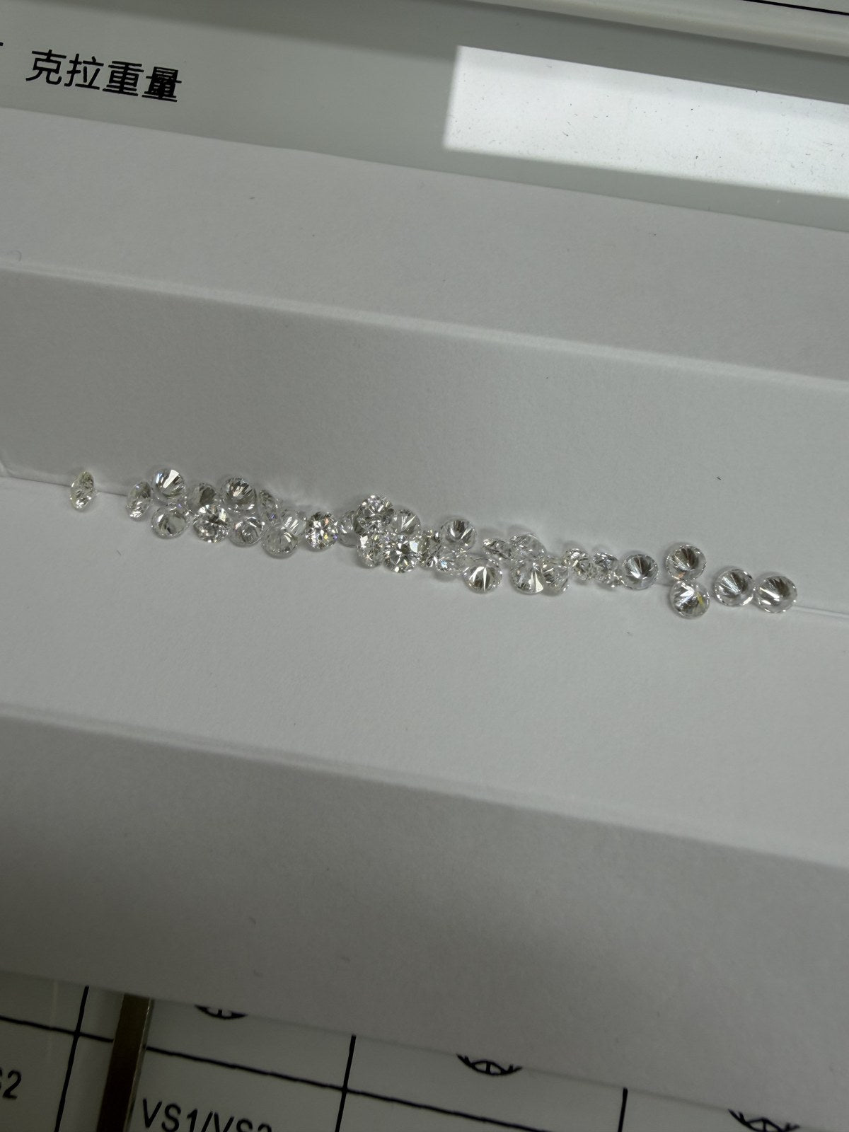 Round lab-grown diamonds, DE VS-VVS, on an inspection tray