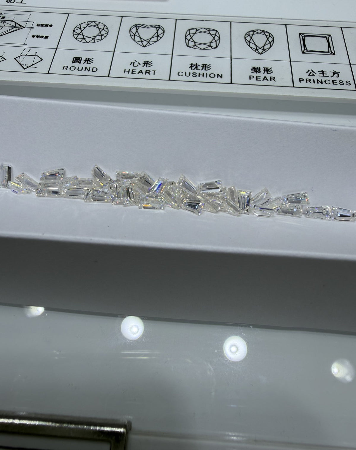Trapezoid lab-grown diamond melee, DE VS-VVS, on an inspection tray